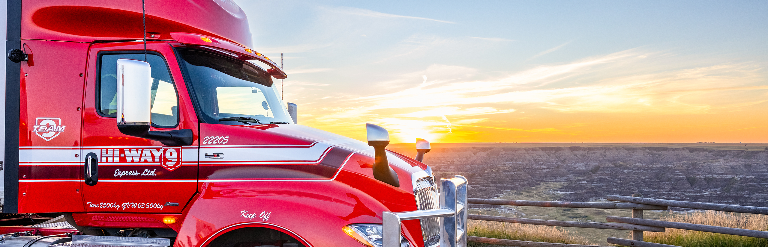 Side view of Hi-Way 9 truck cab in front of Western Canadian landscape during sunset